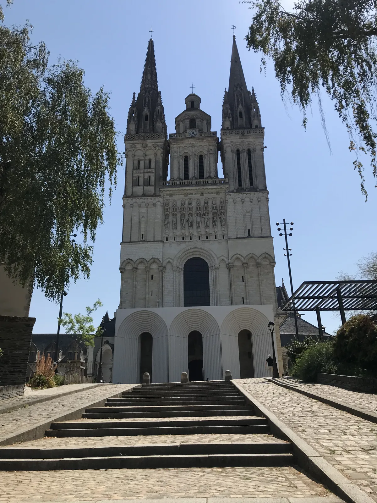 La façade de la cathédrale Saint-Maurice, ses deux flèches et sa tour centrale, au-dessus de la galerie blanche à arches bâtie devant le portail, vue du bas de la montée Saint-Maurice
