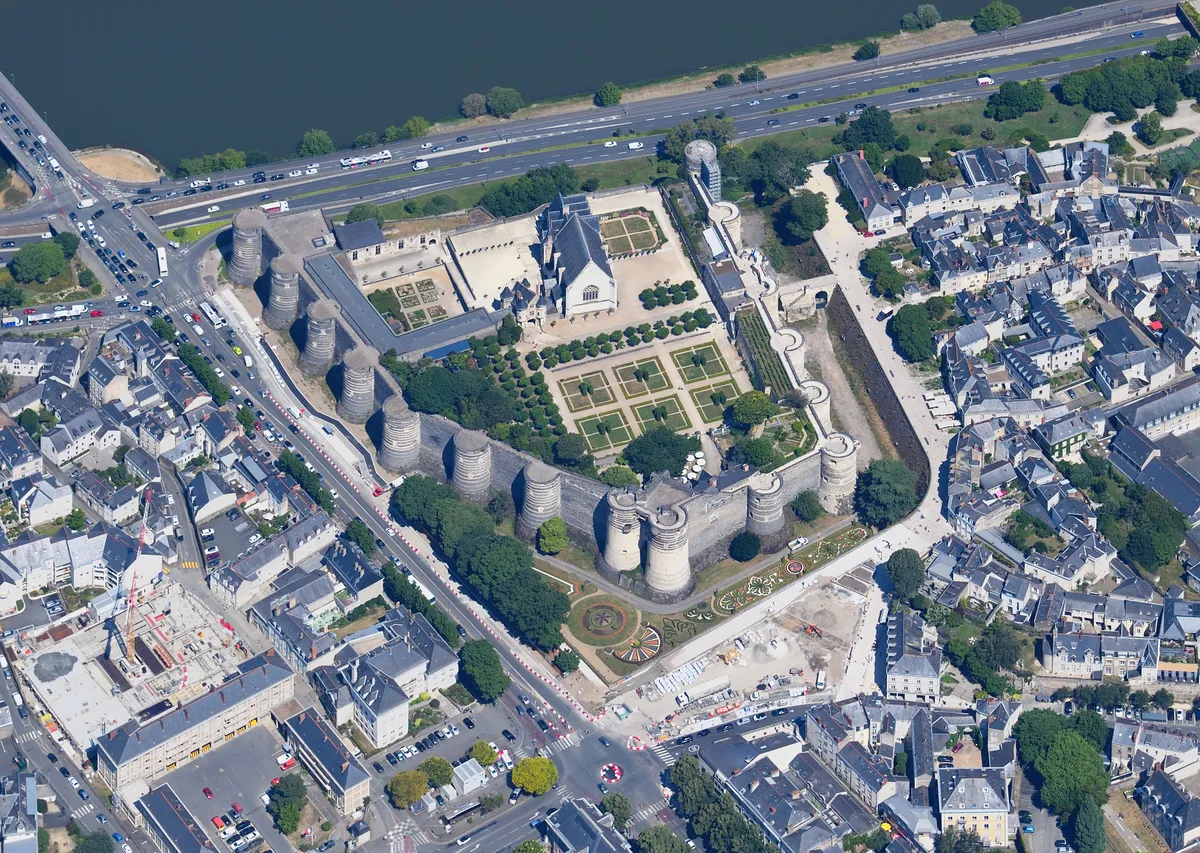 Vue aérienne du château d'Angers : l'enceinte et ses tours sombres, les jardins à la française dans la cour et la Maine en haut de l'image