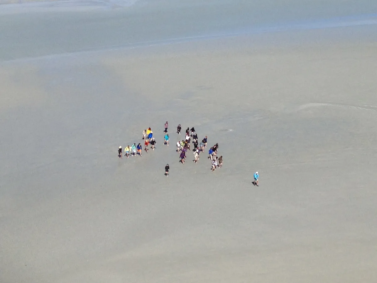 Un groupe de marcheurs dans les grèves, vu depuis la tour Nord du Mont-Saint-Michel