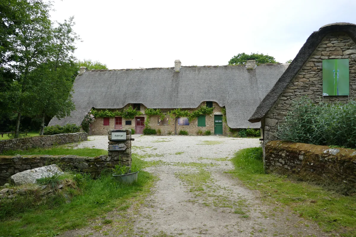 Des chaumières de Kerhinet aux murs de pierre et aux toits de roseau, autour d'une cour de gravier