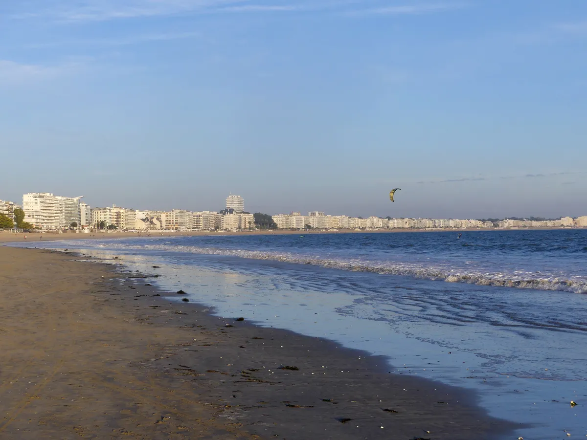 La grande plage de La Baule en fin de journée d'automne, à marée descendante, avec le front de mer au loin et un kitesurfeur dans la baie