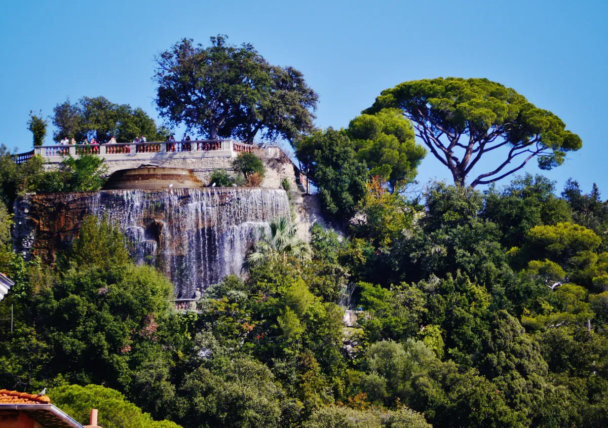 La cascade du parc de la colline du Château dans la végétation, sous les pins parasols