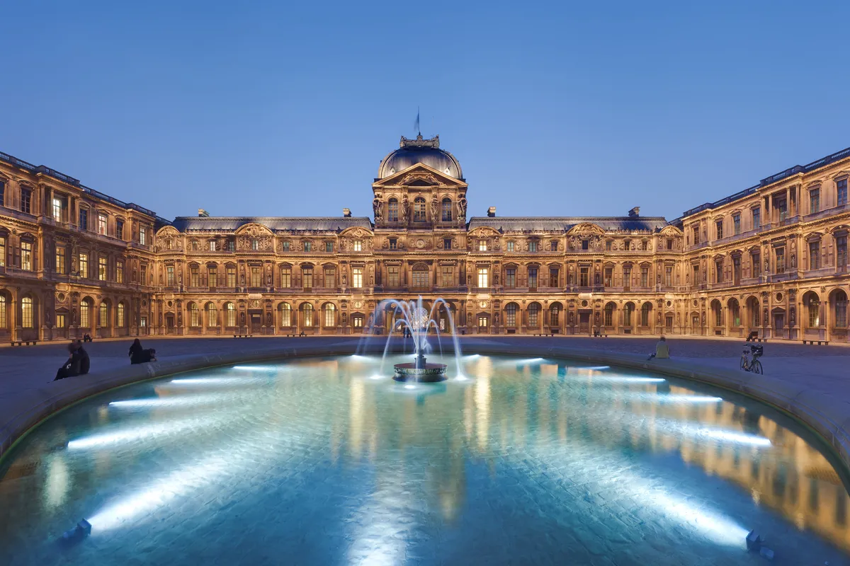 La cour Carrée du Louvre au crépuscule, sa fontaine éclairée et le pavillon de l'Horloge au fond