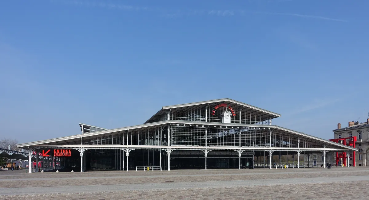 La Grande Halle de la Villette, sa charpente de fonte et de verre, sous un ciel bleu