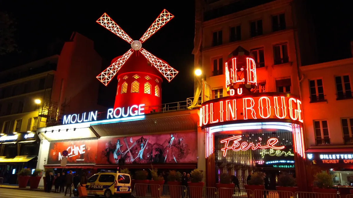 La façade du Moulin Rouge illuminée, de nuit, avec son moulin et ses enseignes