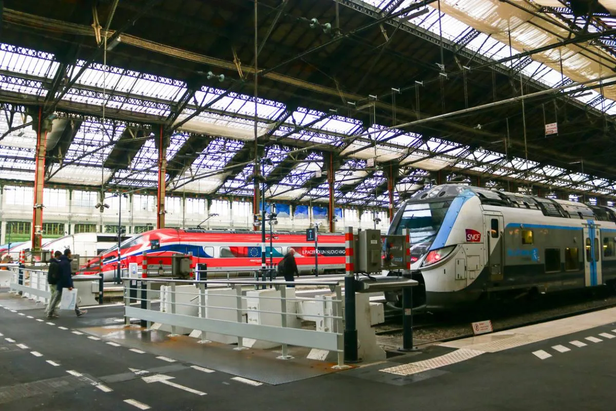 Un train à grande vitesse Frecciarossa et un TER à quai sous la verrière d'une gare parisienne