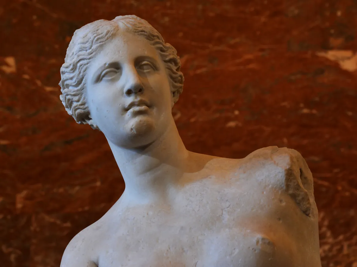 Le buste de la Vénus de Milo sur un fond de marbre rouge
