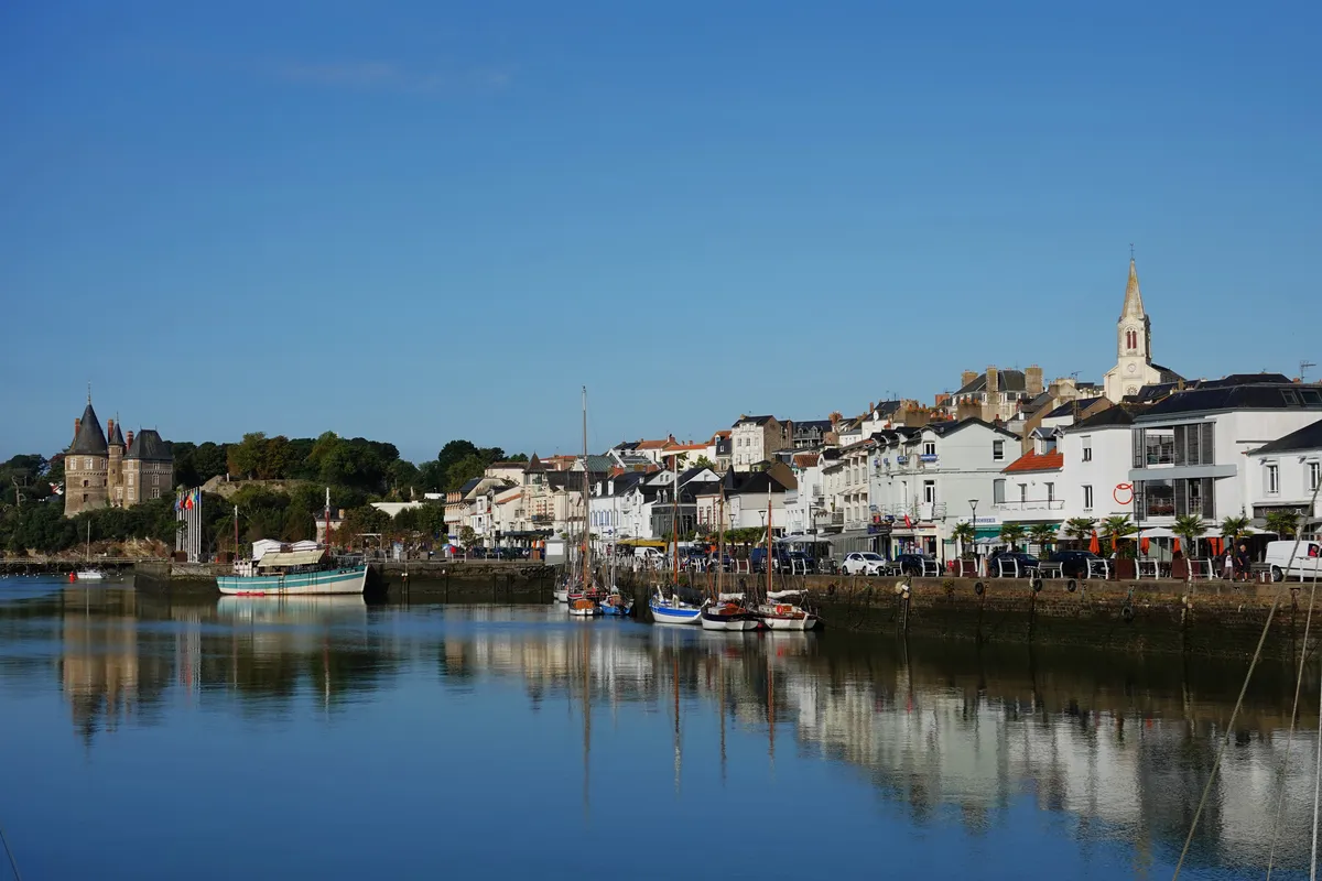 Le vieux port de Pornic à marée haute, ses quais et ses maisons blanches, avec le château à gauche et le clocher de l'église au fond