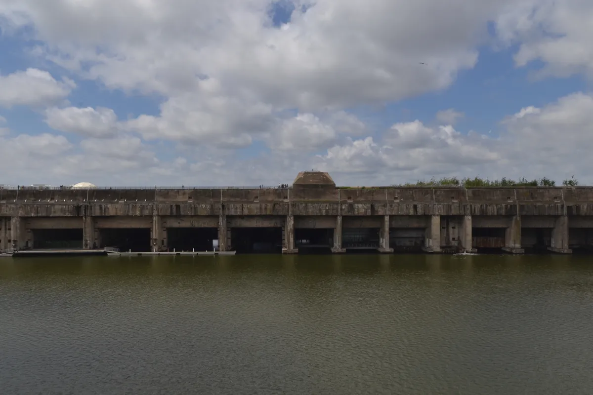 La base sous-marine de Saint-Nazaire, long bloc de béton aux alvéoles ouvertes sur le bassin, vue de la rive d'en face
