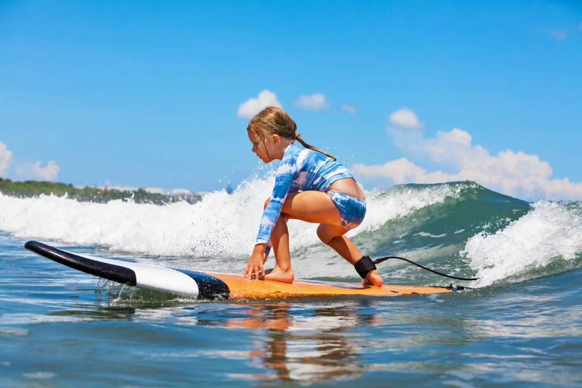 Une jeune surfeuse en équilibre sur sa planche au moment du take-off